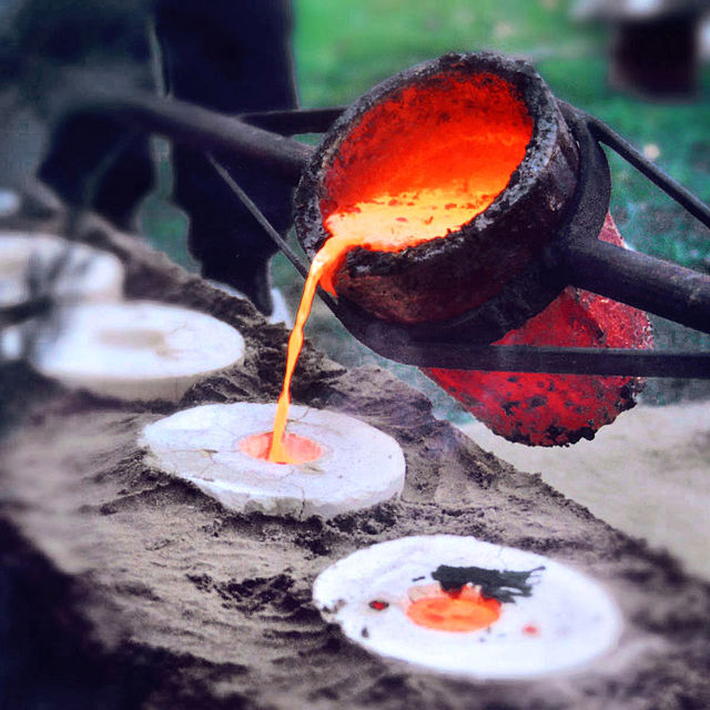 molten bronze being poured into a mold to make a new alloy
